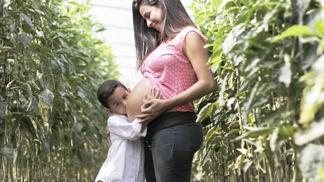 Child kissing pregnant belly for Birth Classes Free